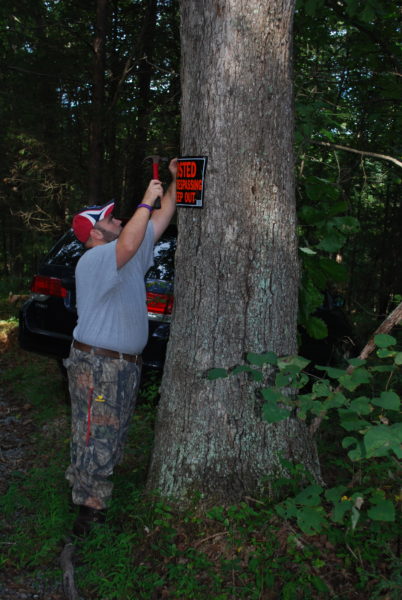 Imagen de un hombre clavando un cartel en un árbol