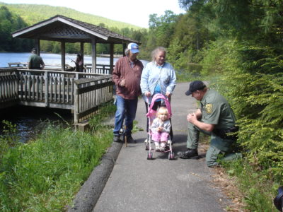 Una imagen de un camino accesible para sillas de ruedas, con un niño pequeño en un cochecito rosa en el camino