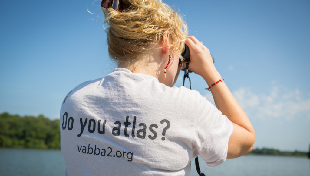 Una mujer con binoculares realizando un estudio de observación de aves en Virginia en Amelia WMA
