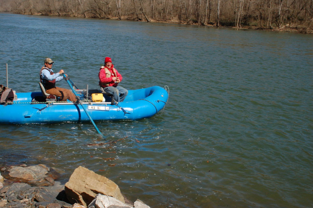Una imagen de dos hombres en una balsa azul pescando cerca de una piscina rocosa profunda