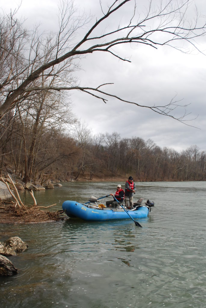 Una imagen de dos personas pescando con chalecos salvavidas rojos en una balsa azul en New River; Es importante viajar con un amigo al aire libre, especialmente en condiciones climáticas o temperaturas peligrosas.
