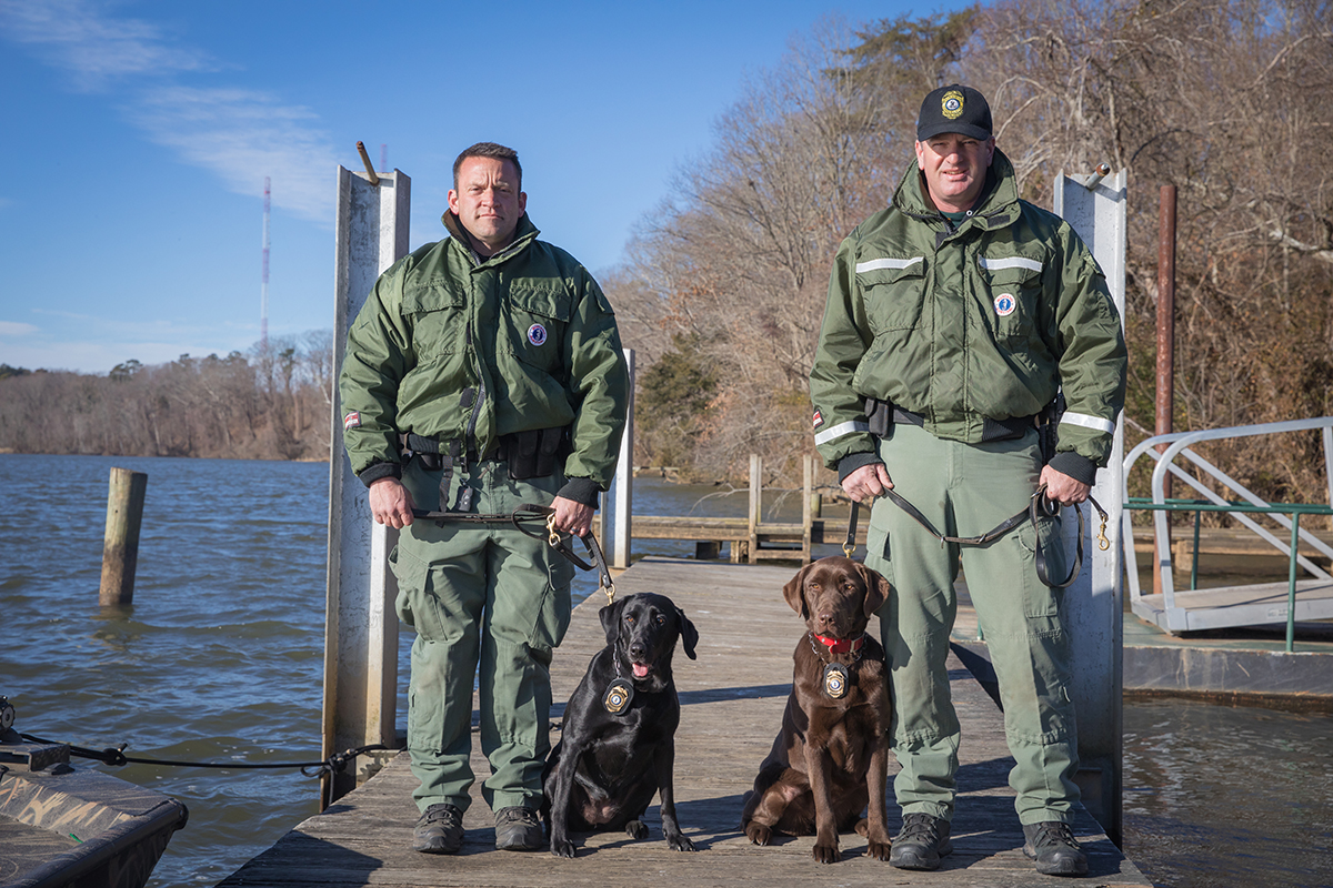 El CPO James Patrillo y K9 Bailey (izquierda) y el CPO Senior Wes Billings y K9 Molly en un muelle.