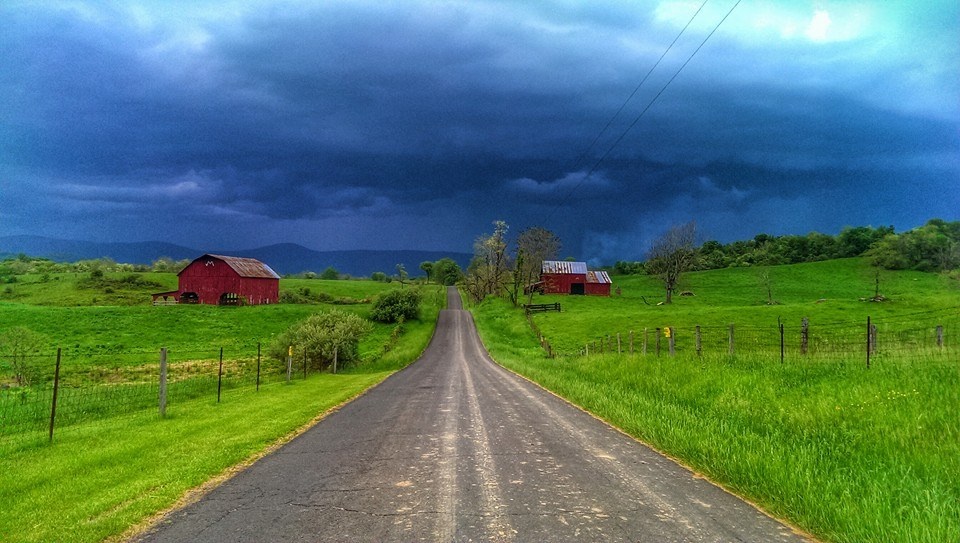Una imagen de un camino rural con graneros visibles en el fondo