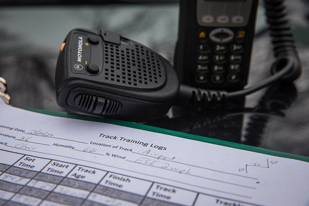 Una imagen de una unidad GPS, un dispositivo de comunicación y un registro de entrenamiento Track en una mesa de cristal