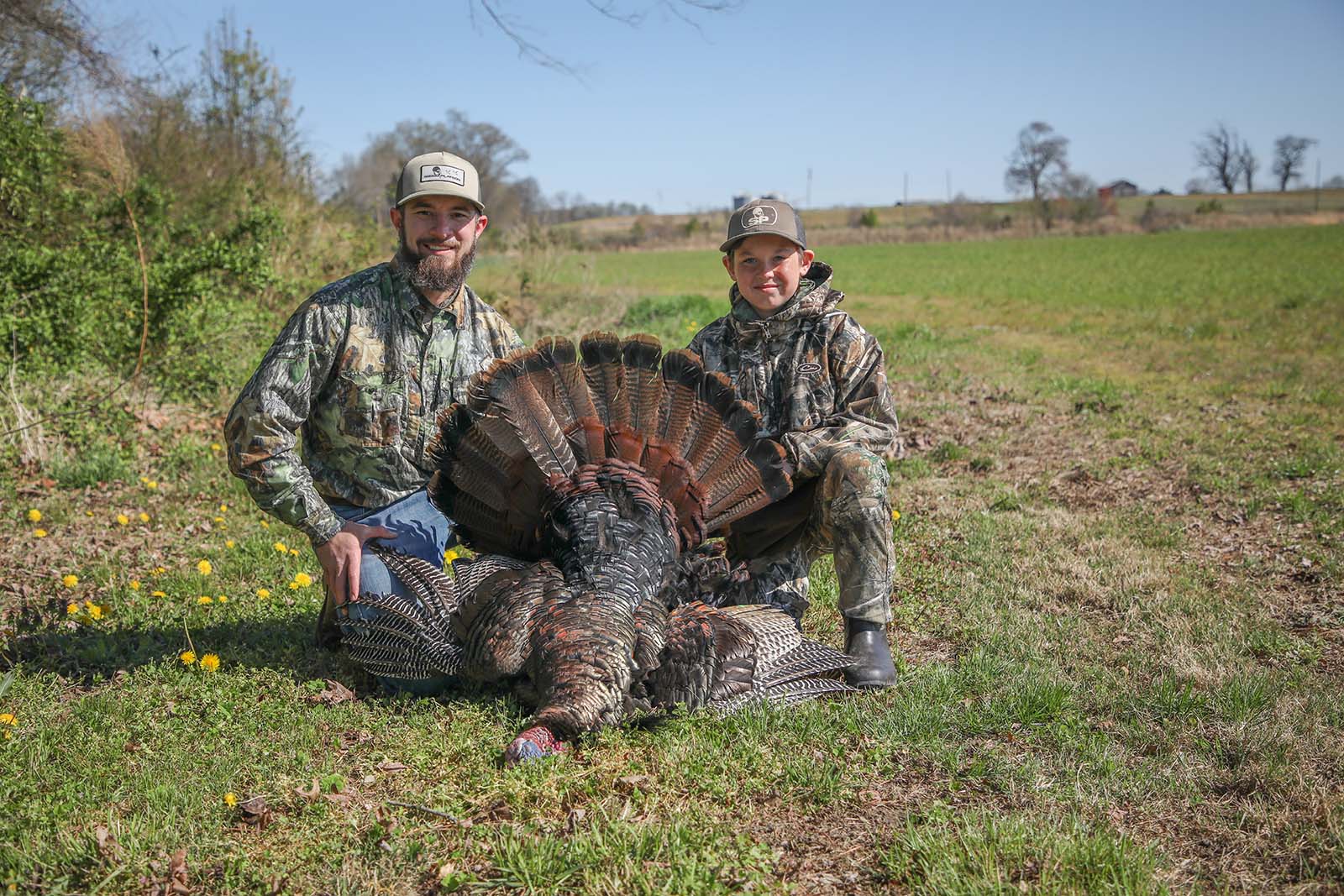 Un hombre y un niño con un pavo cosechado
