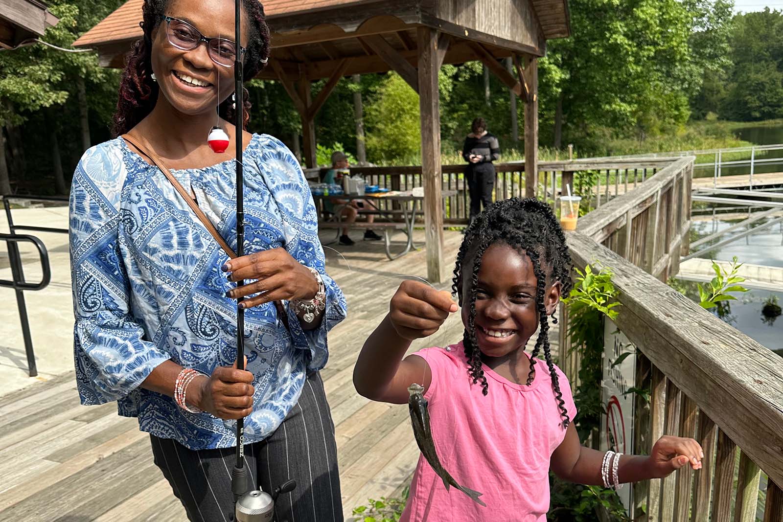Una mujer y un niño sosteniendo una caña de pescar y un pez