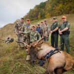 Ocho hombres posando con un alce muerto.