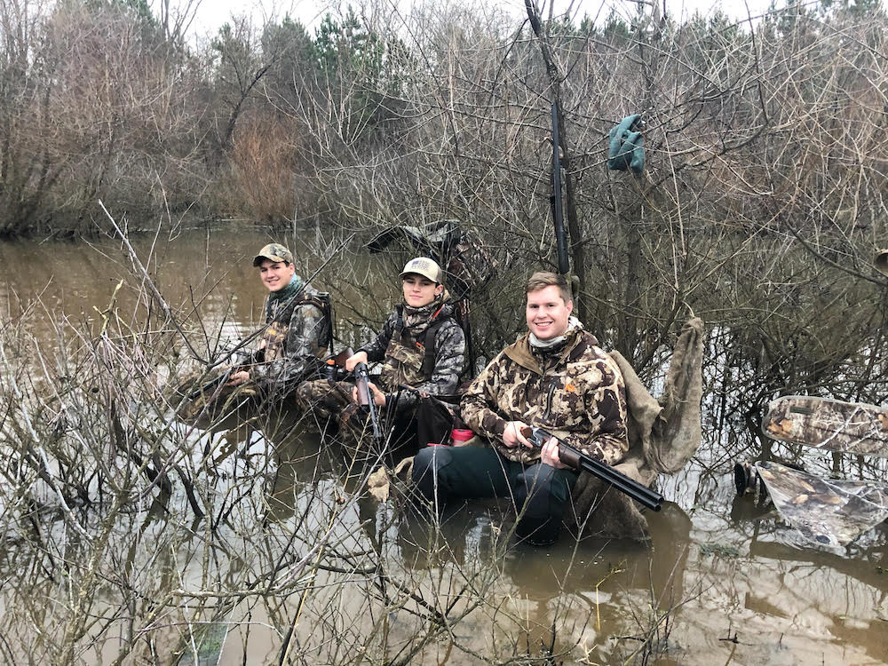 Una imagen de un grupo de hombres sentados en un tronco en el agua, esta vez no encontraron un pato