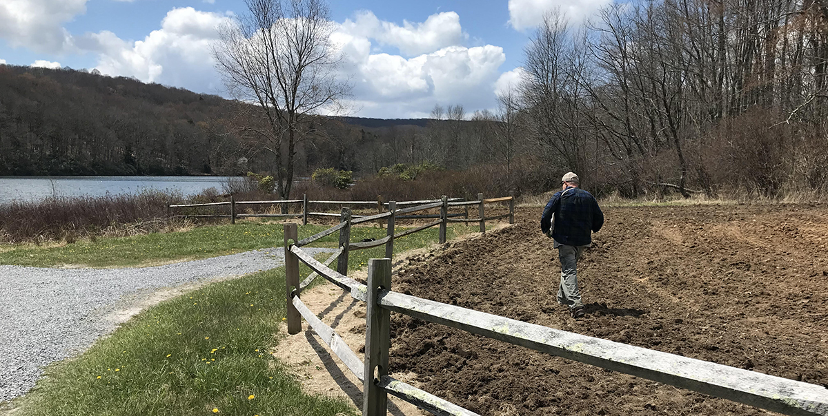 Un miembro del personal del DWR distribuyendo fertilizante y semillas en el suelo con discos.