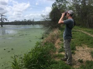 Una persona con prismáticos mirando al otro lado de un estanque