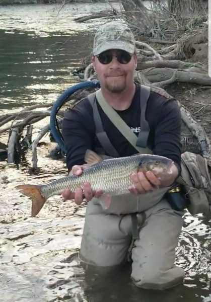 Una imagen de Jerry Hall en un humedal sosteniendo su récord estatal de pez catarata