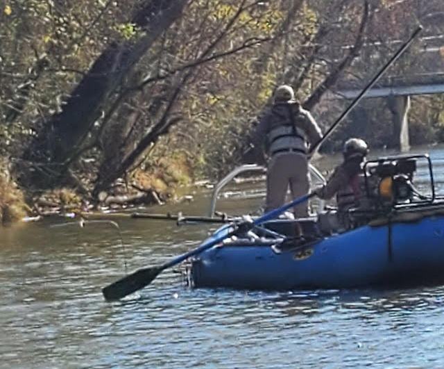 Dos hombres en un bote de pesca eléctrica azul en el agua
