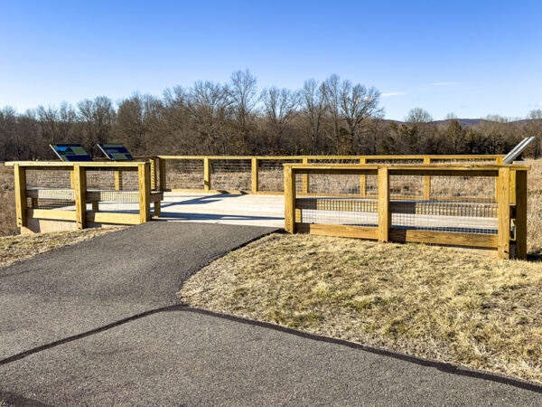 Mostrador de observación de madera al final de un camino asfaltado con vistas a un humedal en invierno.