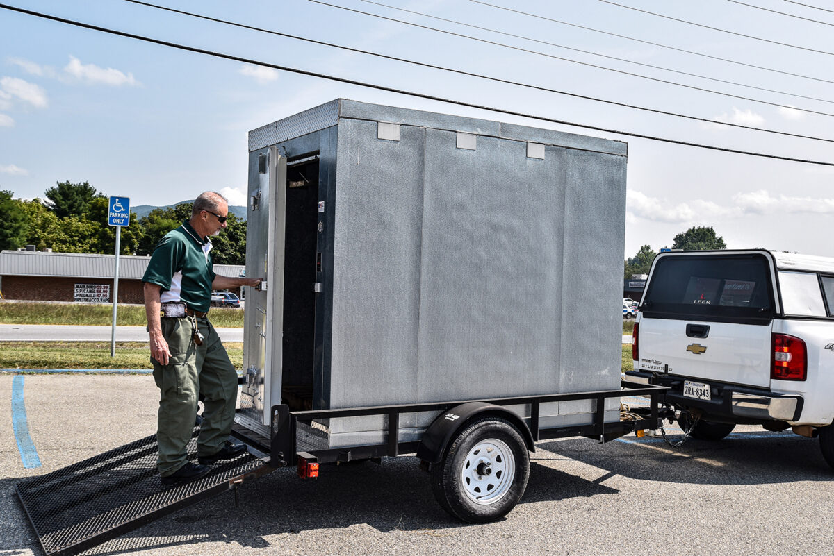 Una imagen de Gary Arrington de pie en la rampa de un remolque de metal que contiene una caja fría móvil.