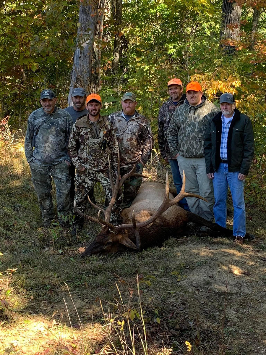 Un grupo de siete hombres de pie junto al alce toro que atraparon