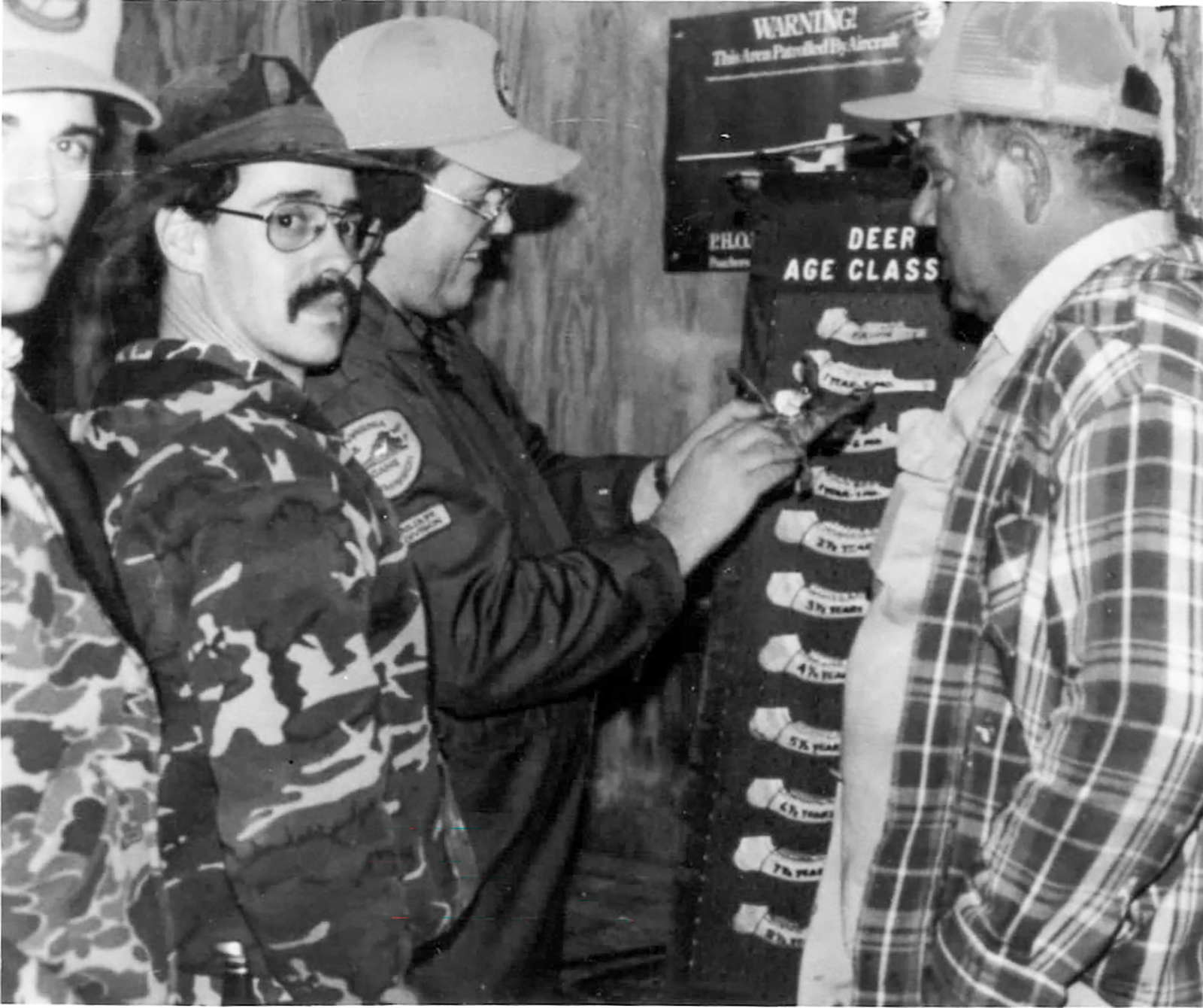 Una imagen antigua en blanco y negro que muestra a cazadores midiendo la mandíbula de ciervo.