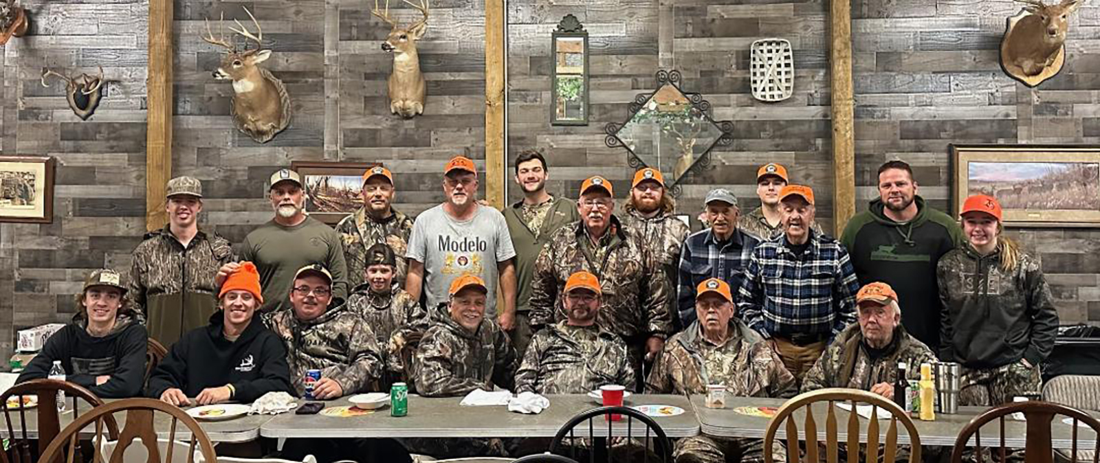 Una foto de 19 hombres todos vestidos de camuflaje, sentados y de pie tras una mesa larga.