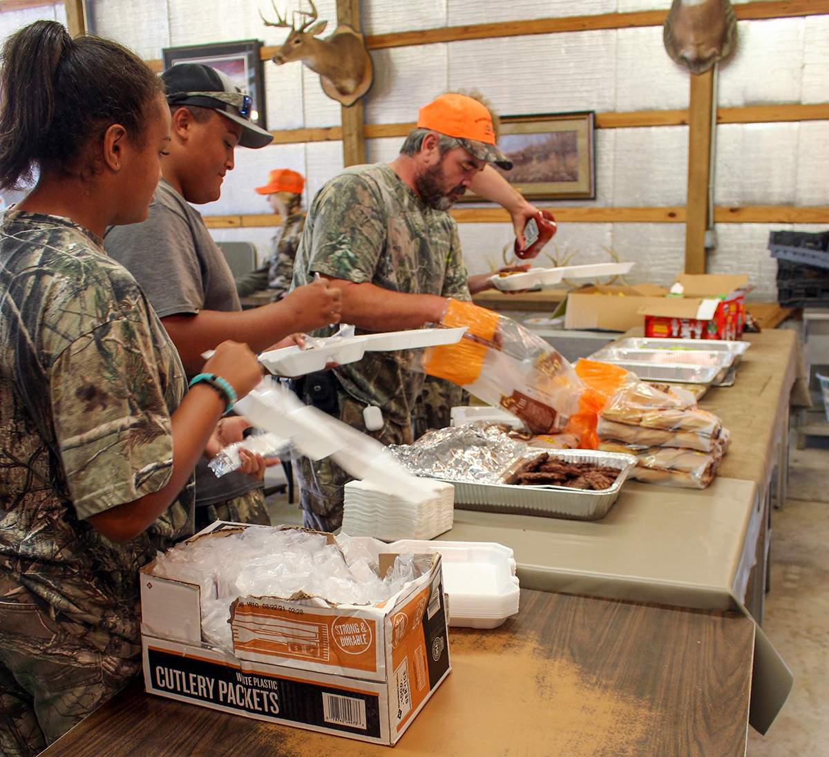 Una foto de tres personas trabajando juntas para preparar comida.