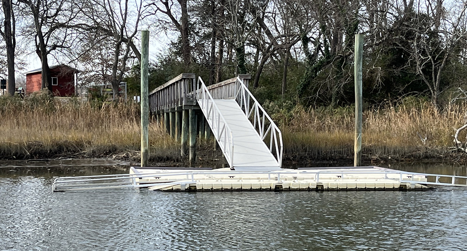 Una foto de una lancha de kayak de aluminio que sobresale en el agua de un río desde la orilla.