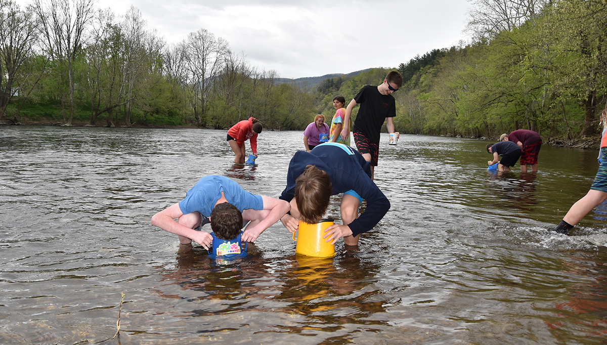 Una imagen de varios estudiantes mirando al agua con binoculares como parte del día salvaje del Proyecto en el río James.