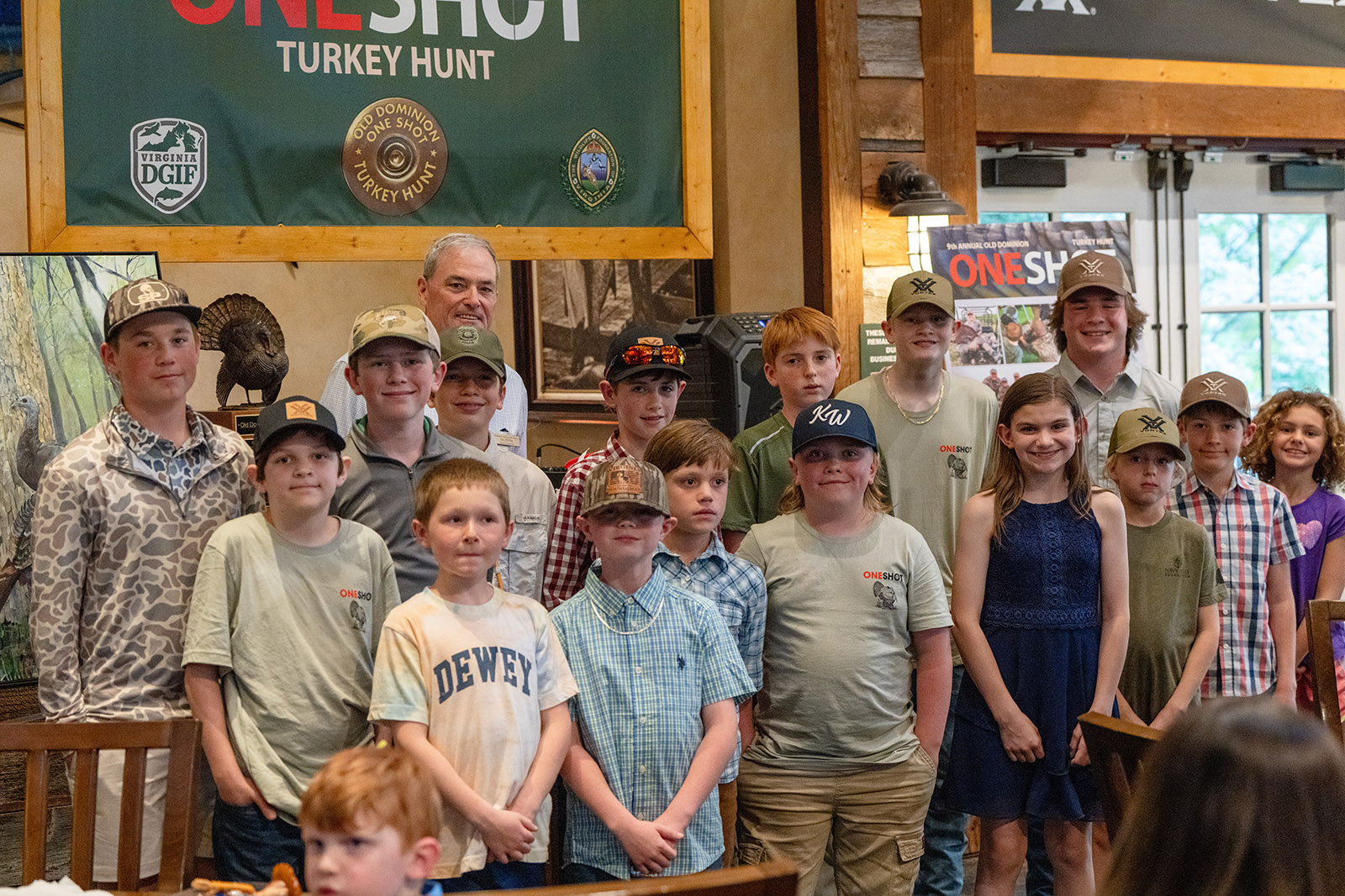 Una foto de un grupo de jóvenes frente a una pancarta de One Shot Turkey Hunt.
