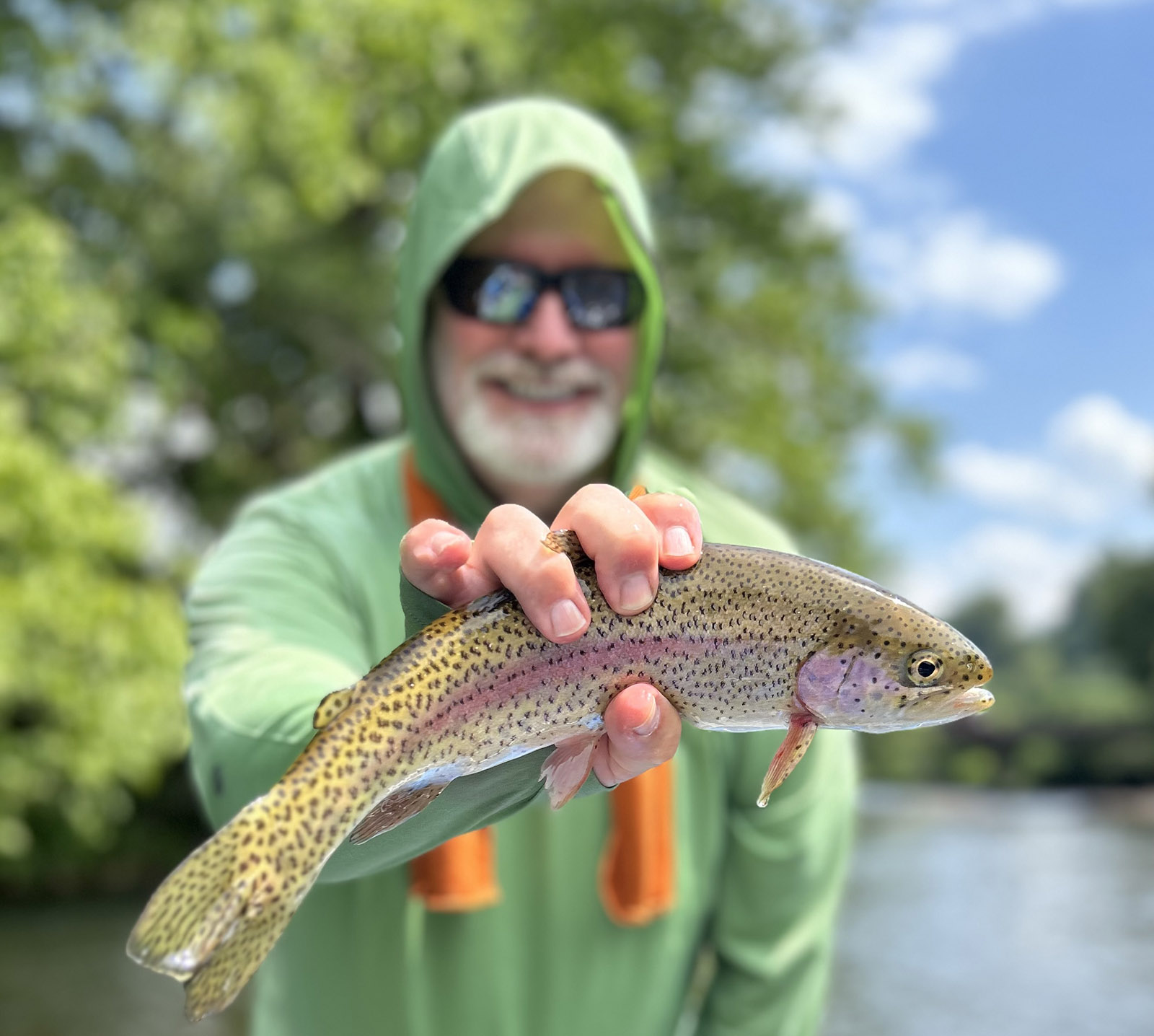 Una foto de un hombre sosteniendo una bonita trucha arco iris fuera del agua.