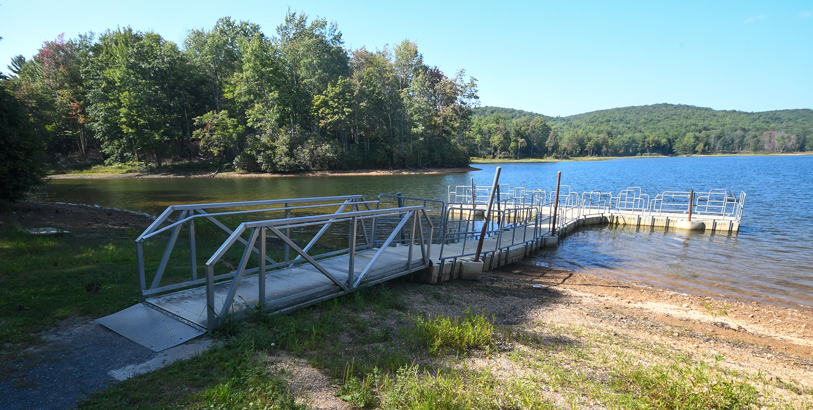 Una foto de un muelle de pesca de metal accesible que se proyecta sobre un gran lago.