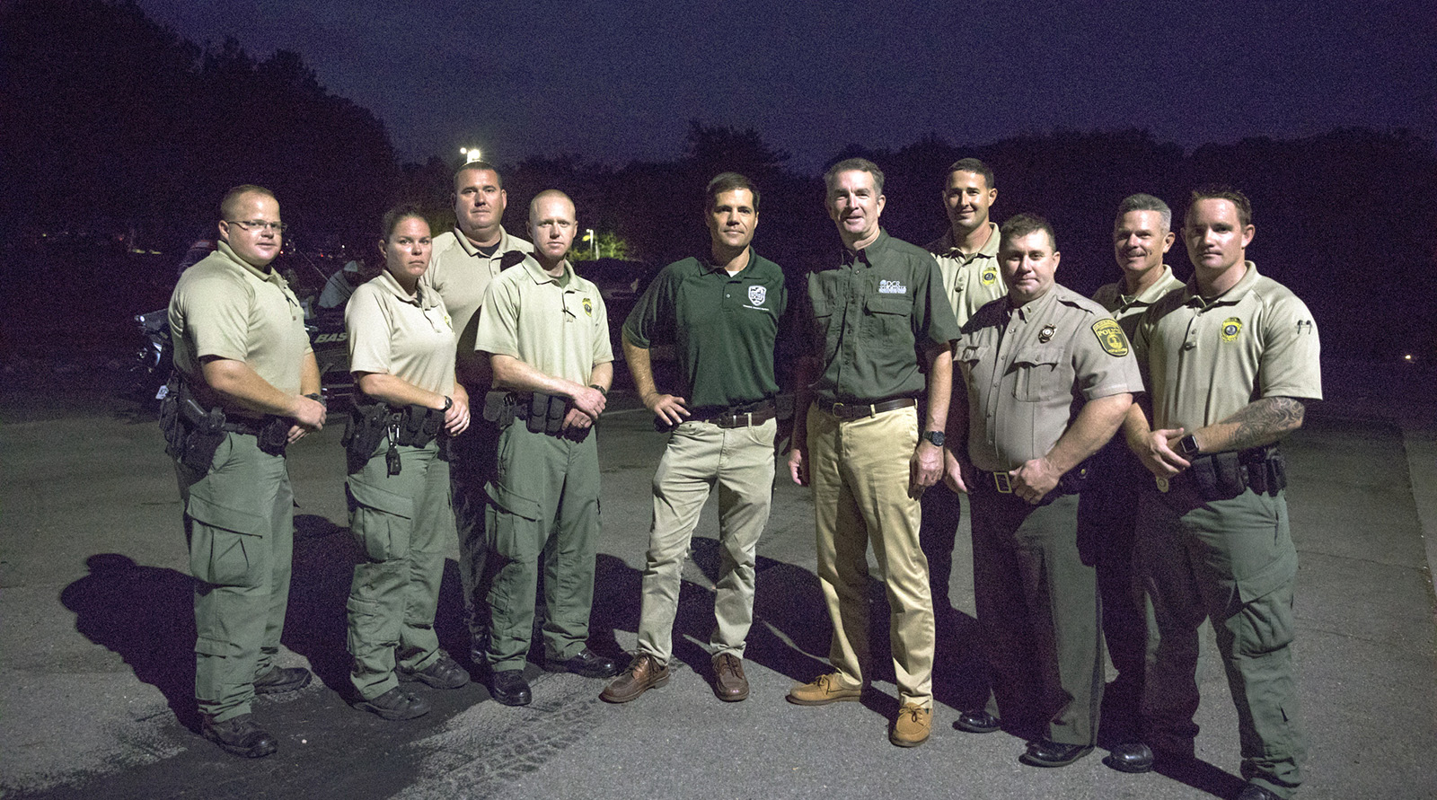 Una foto de Ryan Brown (centro) y el gobernador Northam con ocho oficiales uniformados de la Policía de Conservación.