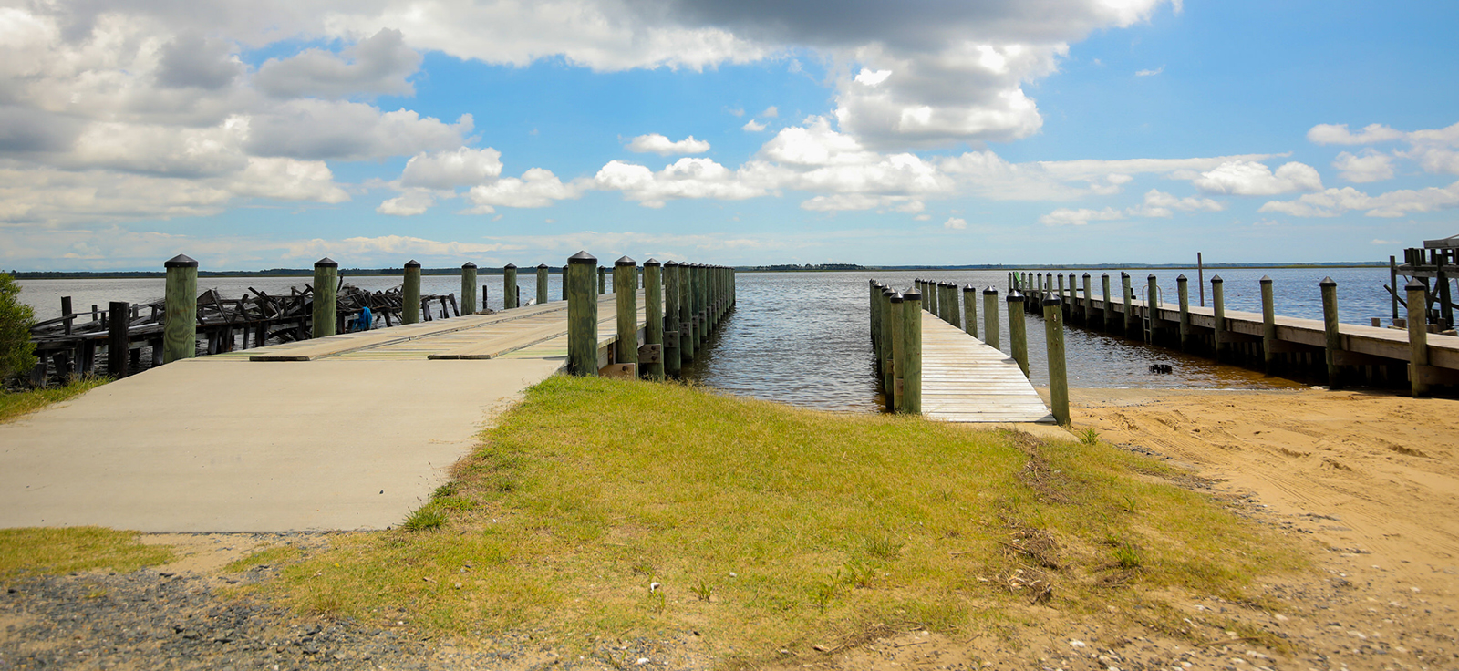 Una foto de una rampa para botes a la derecha y un muelle a la izquierda que se extiende hacia el agua.