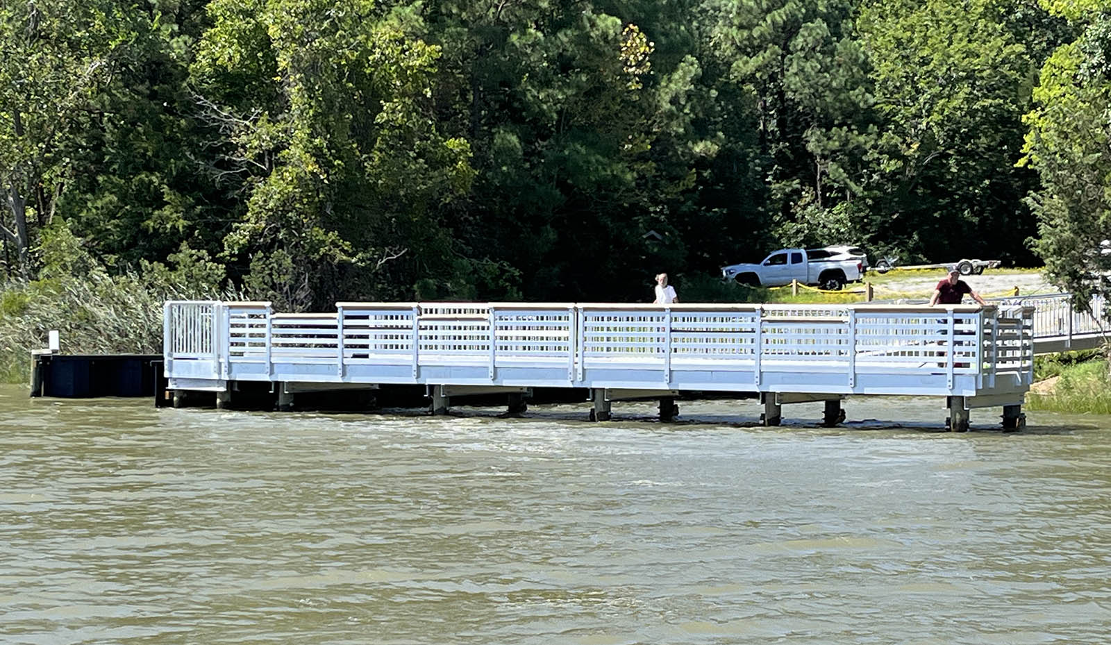Una imagen de un hombre con una camisa roja de pie en un muelle de pesca de metal blanco