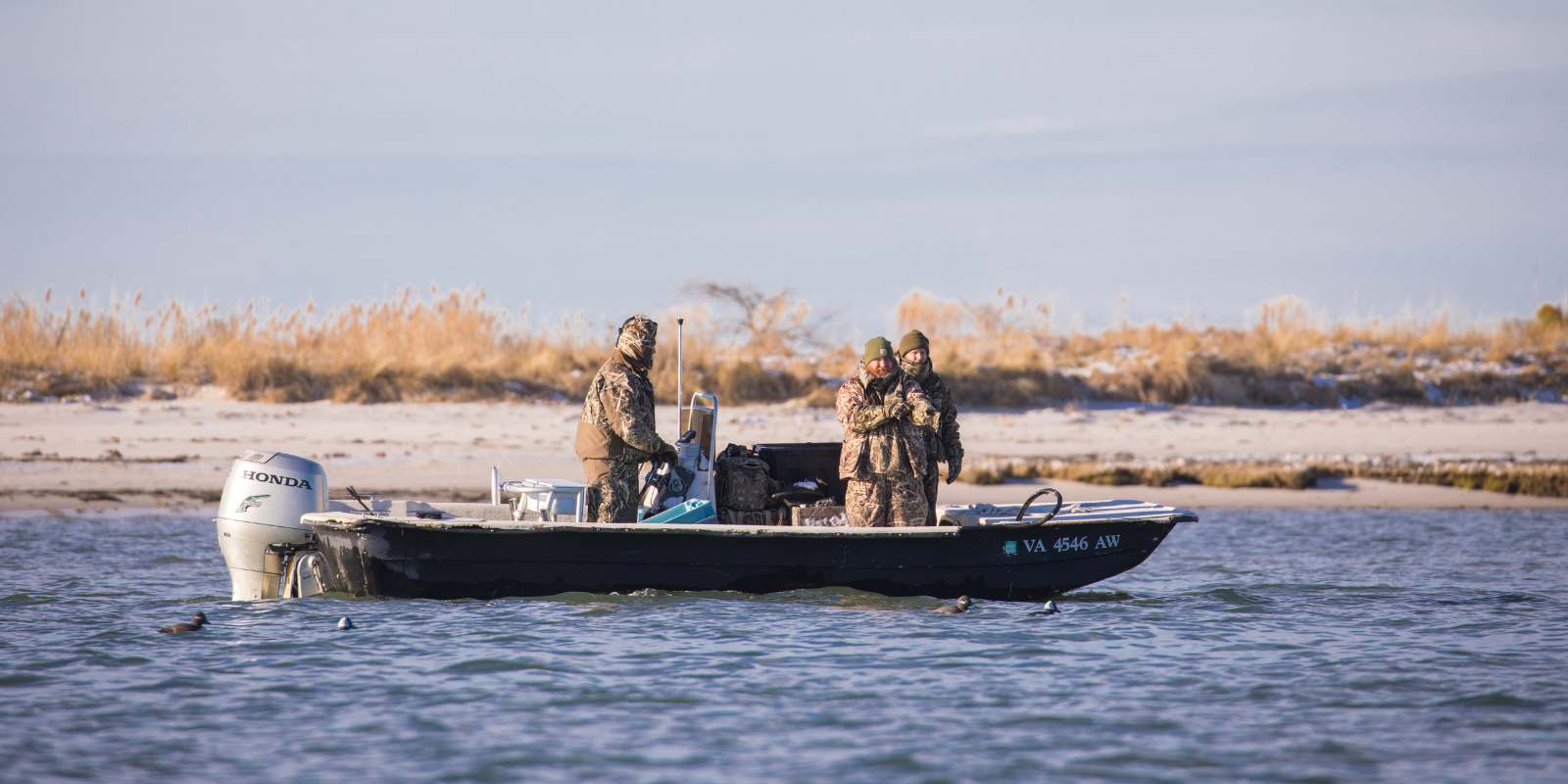 Tres personas en un bote en un día frío con problemas de motor