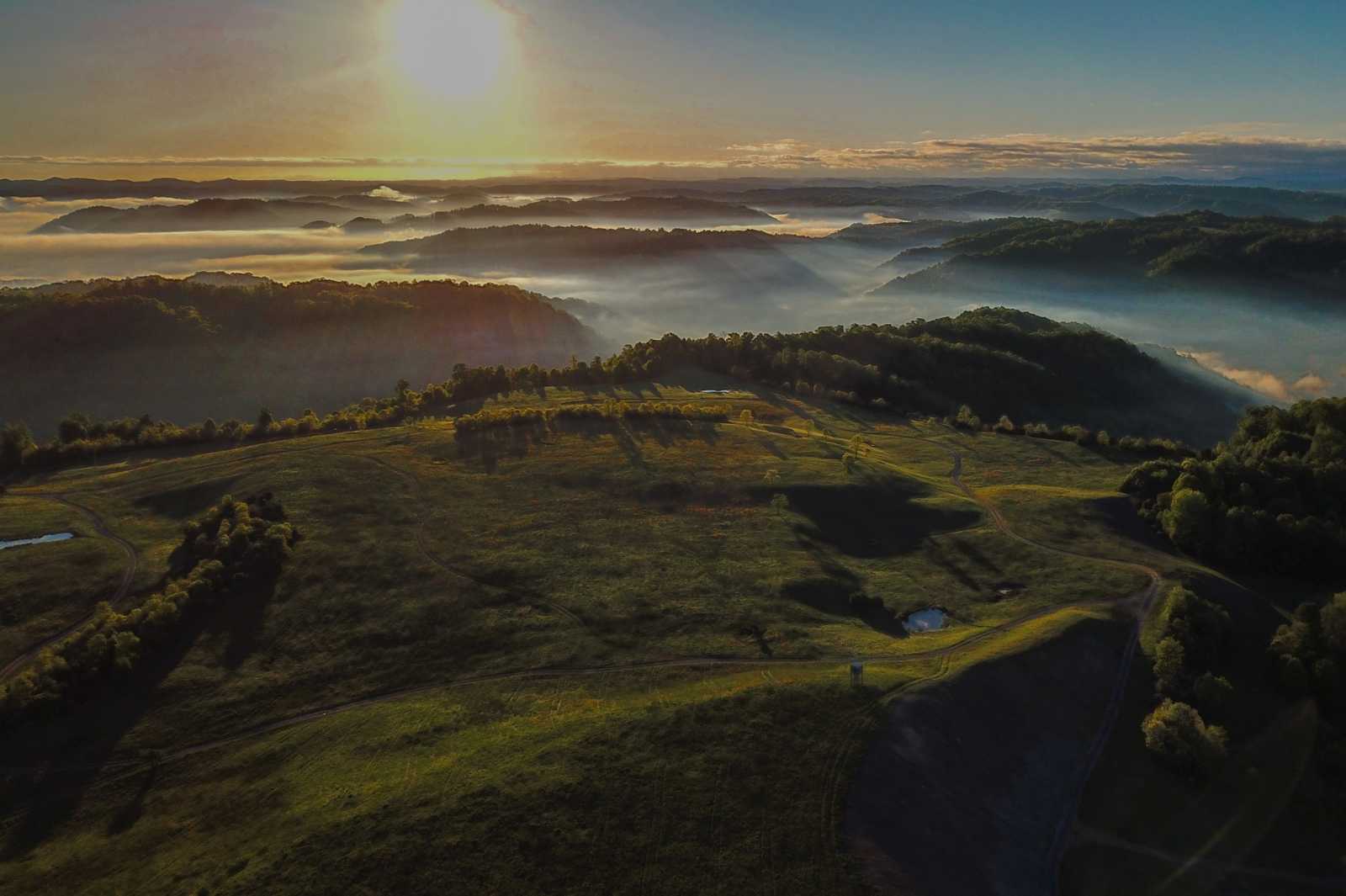 Una hermosa foto aérea escénica de las cimas de las montañas boscosas rodeadas de niebla.