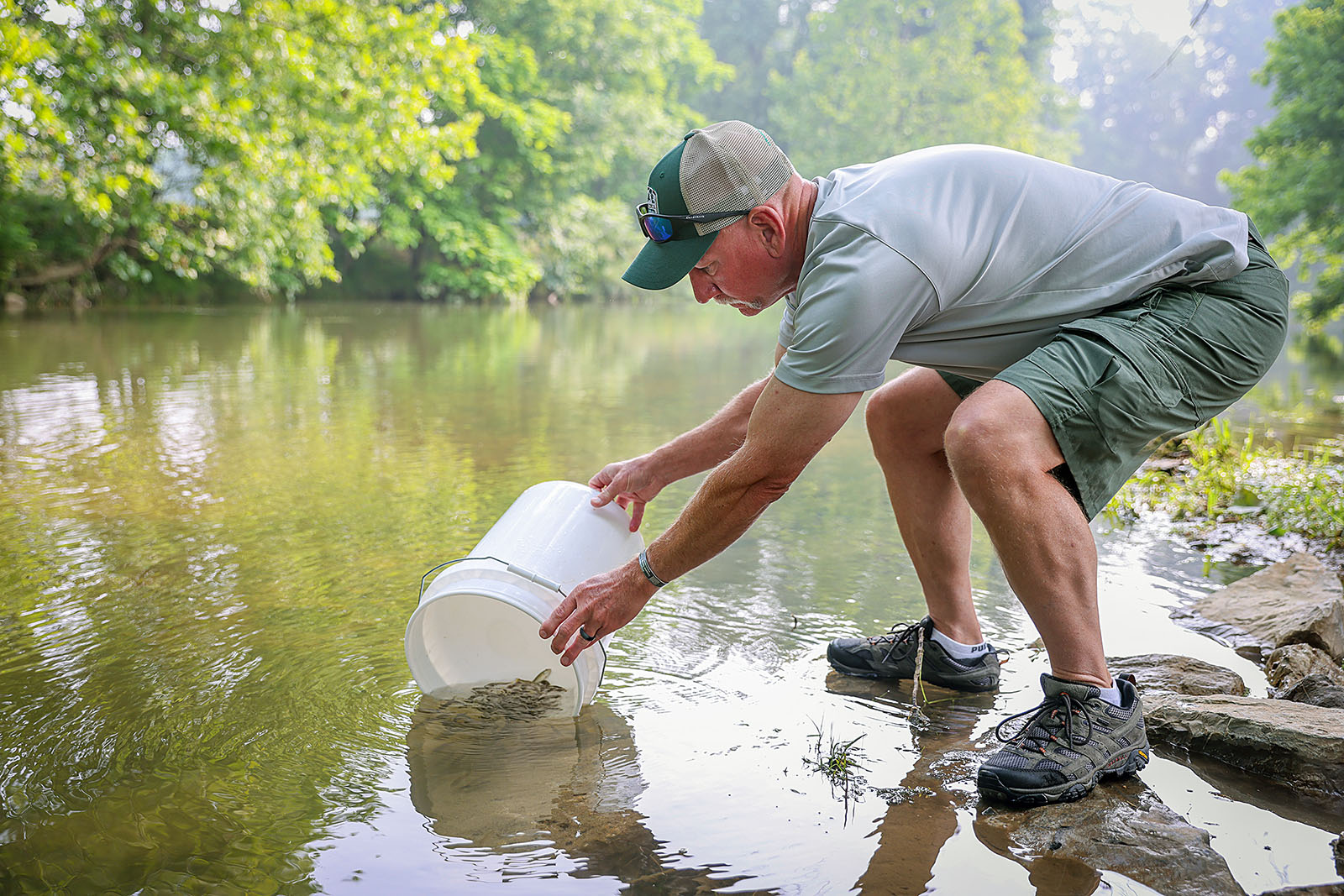 Imagen de un hombre usando un pequeño cubo para llevar lubina a un río