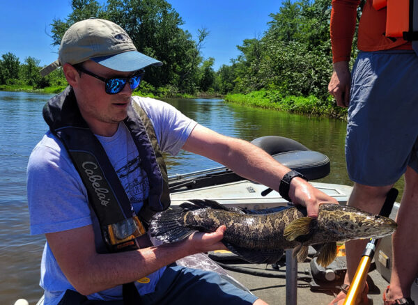Un pescador de Virginia sosteniendo una cabeza de serpiente del norte que atrapó.